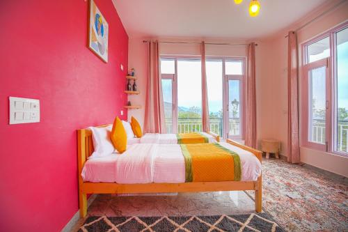 a bedroom with pink walls and a bed with yellow pillows at The Bunksters Bir in Bīr