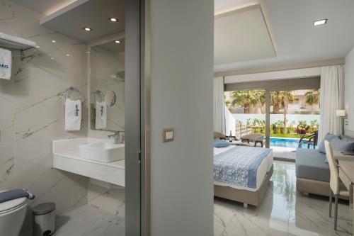 a bedroom with a bed and a bathroom with a mirror at Vantaris Blue adults only in Kavros