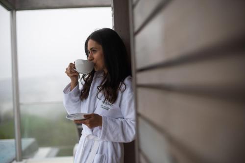 a woman drinking a cup of coffee in front of a mirror at Mahorko Wein Wellness Wasserbüffel in Glanz an der Weinstraße 