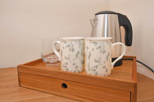 two mugs sitting on a wooden stand with a coffee pot at The Masons Arms in Newcastle under Lyme