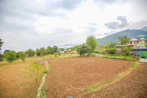 an empty field in a village with houses and mountains at The Bunksters Bir in Bīr