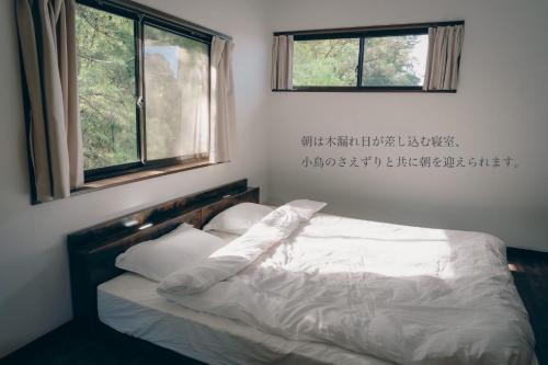 a bedroom with a bed with white sheets and two windows at GUEST HOUSE Ichinoyado - Vacation STAY 39544v in Tajimi