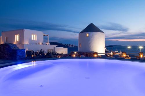 a swimming pool in front of a building at night at Porto Mykonos in Mikonos