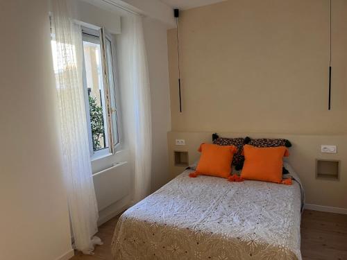 een slaapkamer met een bed met oranje kussens en een raam bij Petit cocon cosy in Bordeaux