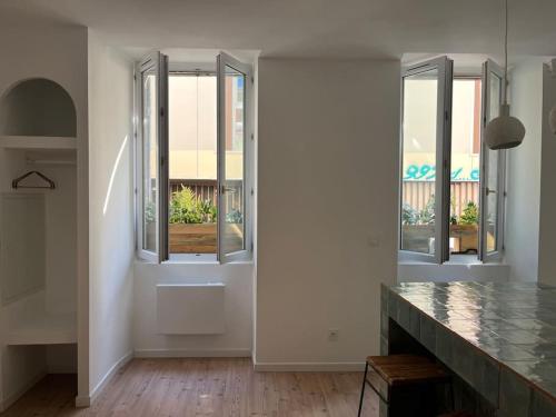 een witte kamer met 3 ramen en een aanrecht bij Petit cocon cosy in Bordeaux