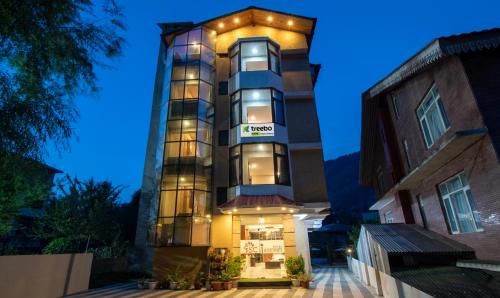 um edifício alto com luzes acesas à noite em Treebo Trend Ambika Residency Near Hidimba Devi Temple em Manali