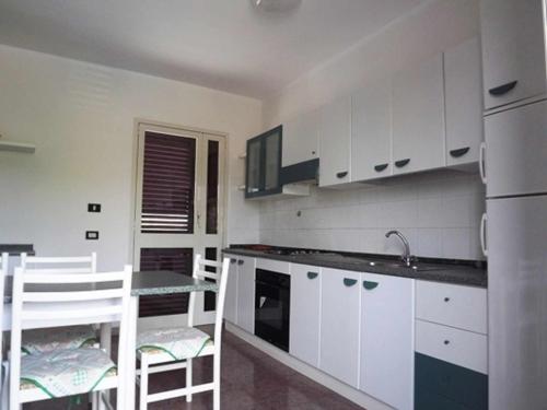 レウカにあるVilletta ristola s m di leucaの白いキャビネット、テーブルと椅子付きのキッチンが備わります。