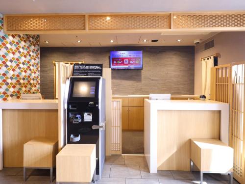 a kitchen with a refrigerator and a bar with a tv at Dormy Inn Tokyo Hatchobori - Natural Hot Spring in Tokyo