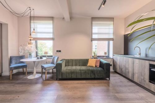 a living room with a green couch and a table at Hof van In & Wellness in Hasselt