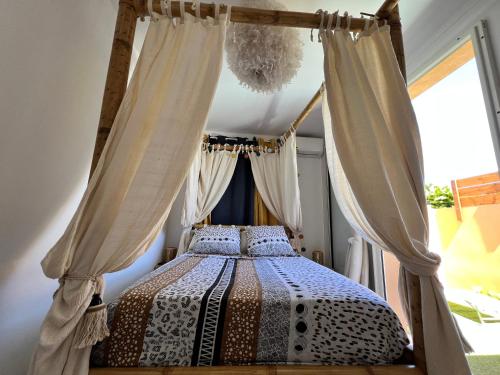 a bedroom with a canopy bed with curtains at Nour Lumière d’Etoile in Saint-Pierre