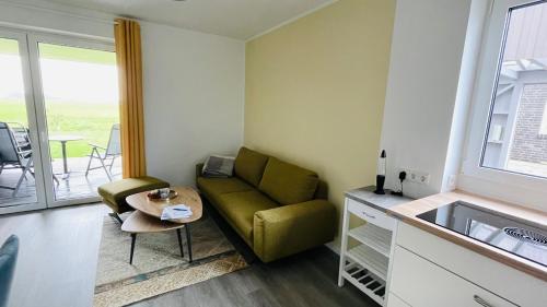 a living room with a green couch and a table at Kleine Burg Ovelgönne in Ovelgönne