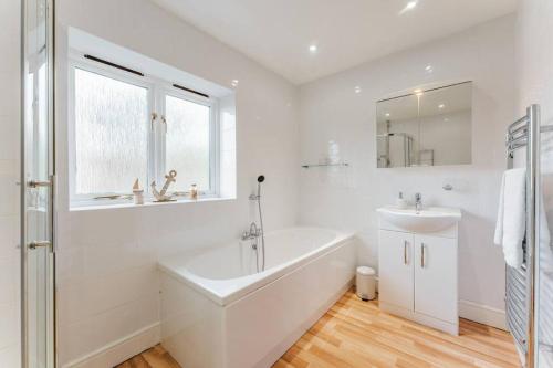 biała łazienka z wanną i umywalką w obiekcie Astley House - Norfolk Cottage Agency w mieście Blakeney