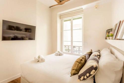 une chambre avec un lit blanc avec des oreillers et une fenêtre dans l'établissement Picasso, rue Debelleyme 4 places, à Paris