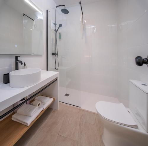 a white bathroom with a sink and a shower at Tres Tocs in Ciutadella
