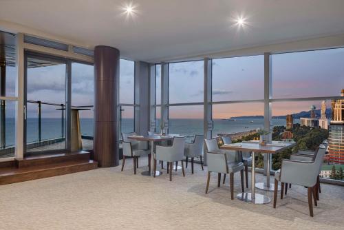 a restaurant with tables and chairs and a view of the ocean at Hilton Batumi in Batumi