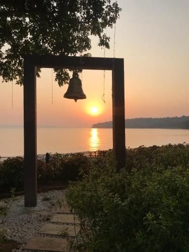 a bell hanging from a tree with the sunset in the background at Grand Hyatt Goa in Panaji