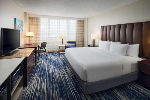 a hotel room with a bed and a flat screen tv at Embassy Suites by Hilton West Palm Beach Central in West Palm Beach