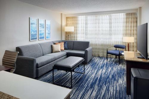 a living room with a couch and a tv at Embassy Suites by Hilton West Palm Beach Central in West Palm Beach