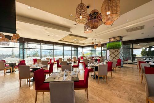 - une salle à manger avec des tables, des chaises et des fenêtres dans l'établissement Wyndham Quito Airport, à Tababela