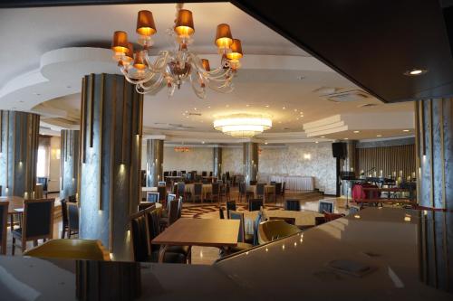 a dining room with tables and chairs and a chandelier at Anadolu Hotels Esenboga Thermal in Esenboga