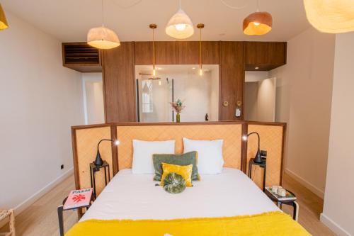 een slaapkamer met een bed met witte lakens en gele kussens bij LOLA Boutique Hôtel - Bordeaux Centre in Bordeaux