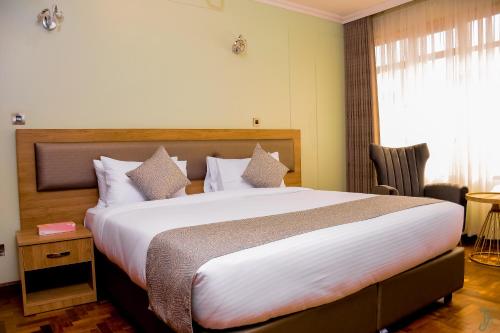 a bedroom with a large bed with white sheets at TJ's Boutique Hotel in Eldoret