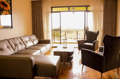 sala de estar con sofá y 2 sillas en TJ's Boutique Hotel, en Eldoret