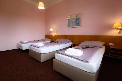 three beds in a hotel room with lights on at Wellness Penzion Kroměříž - Zlobice in Kroměříž