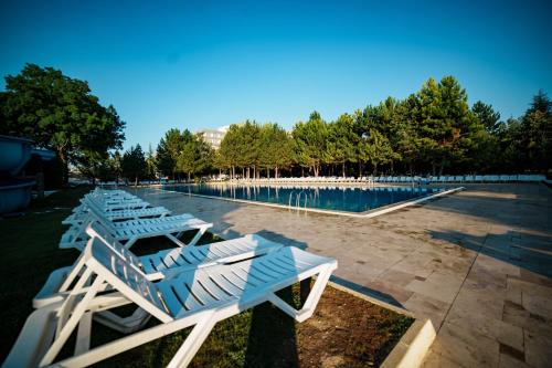 a row of lounge chairs next to a swimming pool at Anadolu Hotels Esenboga Thermal in Esenboga