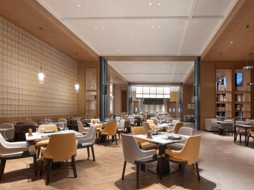 a restaurant with tables and chairs in a room at Novotel Yancheng Exhibition Center in Yancheng