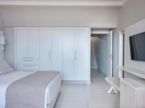 a white bedroom with a bed and a flat screen tv at Atlantica Princess Hotel in Ixia