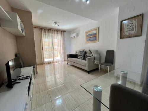 een woonkamer met een bank en een televisie bij ACV - Costa Marina II - 1ª linea planta 6 sur in Oropesa del Mar