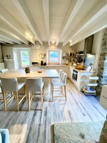 une cuisine avec une grande table en bois et des chaises blanches dans l'établissement GITE DE GROUPE 160m2, 15p, salle de reception, jardin, terrasse, à Mazan-lʼAbbaye