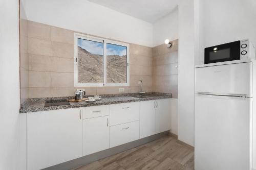 a white kitchen with a sink and a window at Vivienda vacacional La Era Il in Vallehermoso