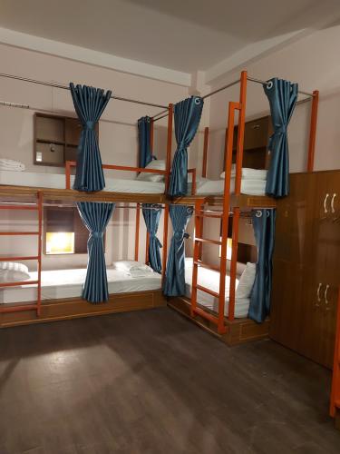 a room with three bunk beds with blue curtains at Saigon Rooftops Hostel in Ho Chi Minh City