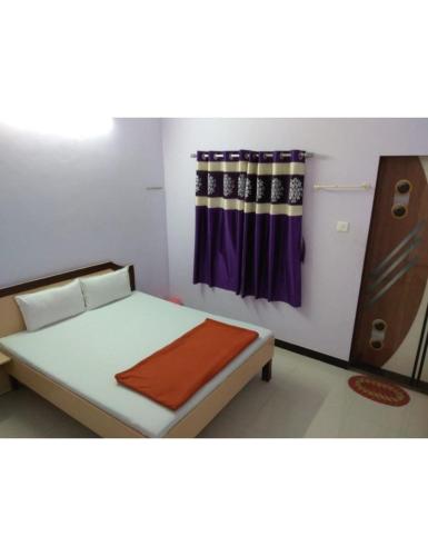 a small bedroom with a bed with a curtain at Excel Hotel, Somnath in Somnath