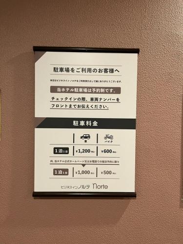 a sign hanging on a wall with writing on it at Business Inn Norte in Sapporo