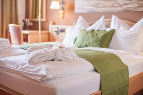 a white bed with green and white sheets and pillows at Mahorko Wein Wellness Wasserbüffel in Glanz an der Weinstraße 