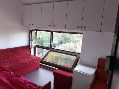 Una sala de estar con un sofá rojo y una ventana. en На пъпа на Варна!, en Varna