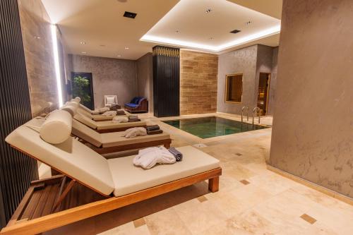 a bedroom with a pool and a bed and a tub at Anadolu Hotels Esenboga Thermal in Esenboga