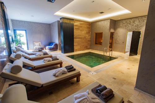 a large room with a pool with a couch and a room with at Anadolu Hotels Esenboga Thermal in Esenboga
