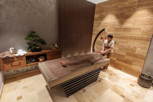 a woman standing next to a bed in a room at Anadolu Hotels Esenboga Thermal in Esenboga