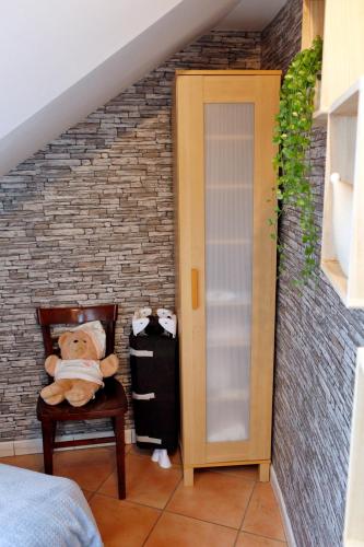 a teddy bear sitting on a chair in a bedroom at B&B Au Coq en Pate in Jalhay