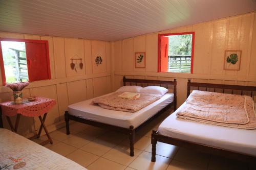 um quarto com duas camas e uma mesa e duas janelas em Fazenda São Matheus em Lauro Müller