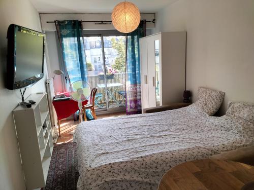 une chambre avec un lit et une télévision à écran plat dans l'établissement Cozy Studio Bastille with balcony, à Paris