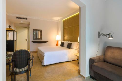 a bedroom with a bed and a chair and a couch at Romano Palace Luxury Hotel in Catania