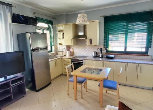 a kitchen with a table and a refrigerator and a table and chairs at HOME SWEET HOME Διαμέρισμα 50τμ σε ήσυχη περιοχή in Orestiada