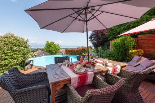 - une table en bois avec un parasol sur la terrasse dans l'établissement La Martichouette Chambres dans Maison vue sur Lac, à Marin