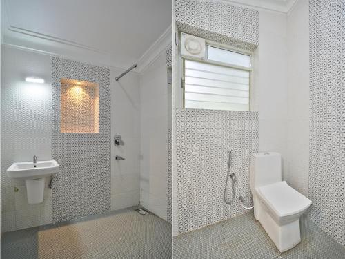 a white bathroom with a toilet and a sink at Calangute By Goa Journey in Calangute