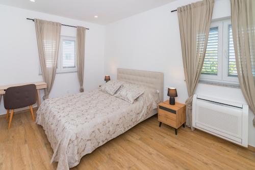 a bedroom with a bed and a desk and windows at Apartman Ana 2 in Vodice